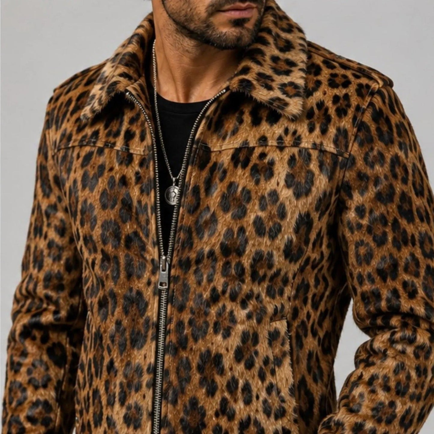 A man wearing a brown and black leopard print zip-up jacket with a fuzzy collar, shown from the chest down against a plain gray background.